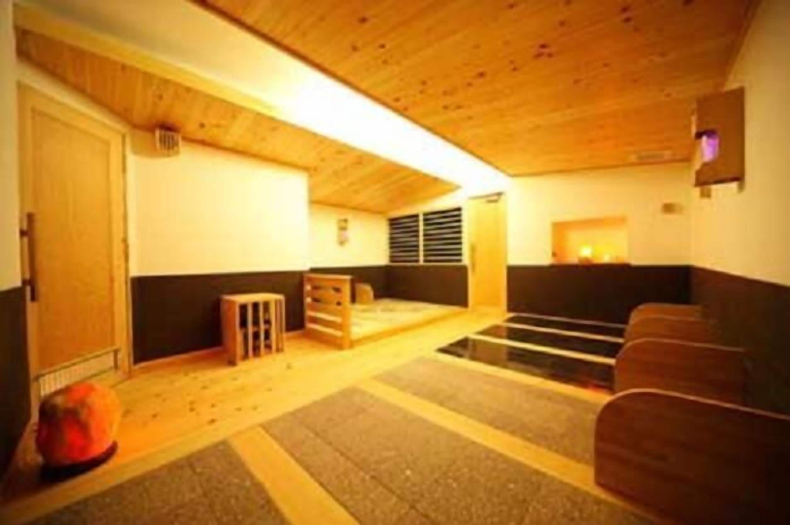 A room with a wooden ceiling, a black couch, a small table, and a radiator.