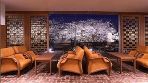 A library with bookshelves, a table, and chairs. - Hotel Park (Gifu)