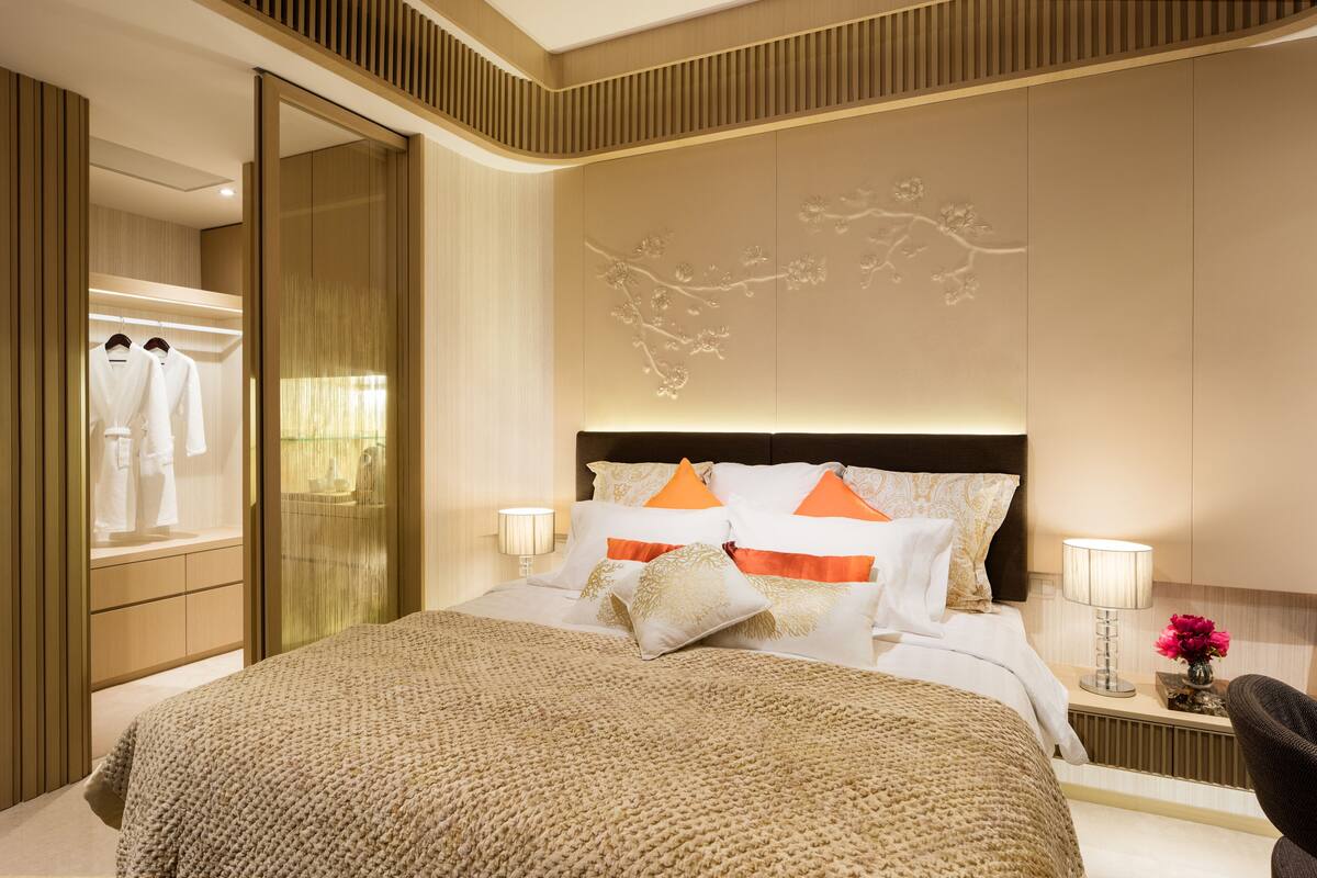 A hotel room with a large bed, a wardrobe, a mirror, and a wall with a floral design.