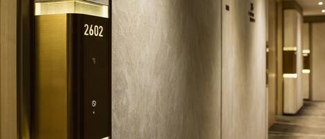 Un couloir d’hôtel moderne avec un ascenseur métallique portant le numéro 2602.