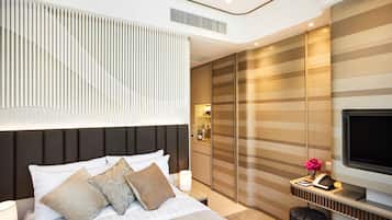 A modern hotel room with a large bed, a TV, a desk with a phone, and a wardrobe.