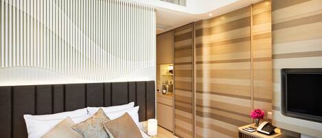 Une chambre d’hôtel moderne équipée d’un grand lit, d’une télévision, d’un bureau avec un téléphone et d’une armoire.