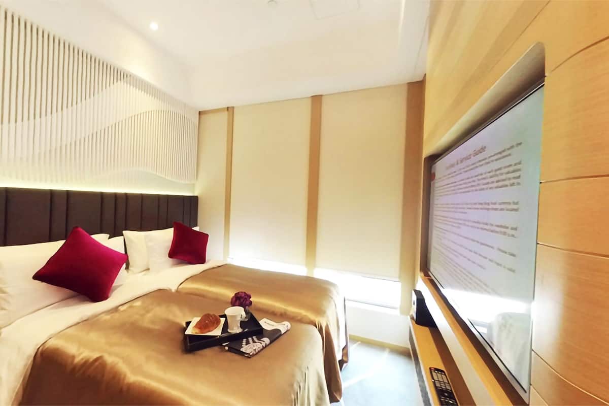 A hotel room with two beds, a TV, and a breakfast tray.