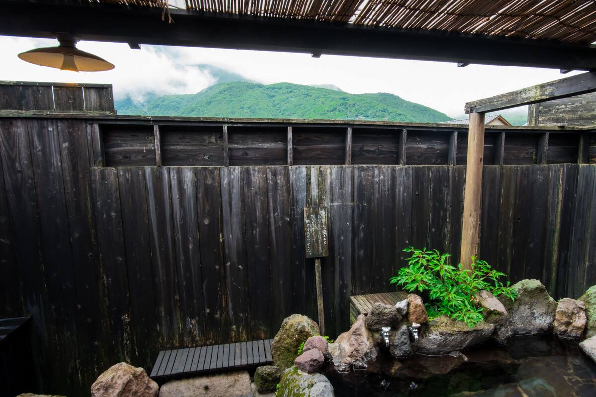 A wooden fence with a stone water feature and a view of a mountain.