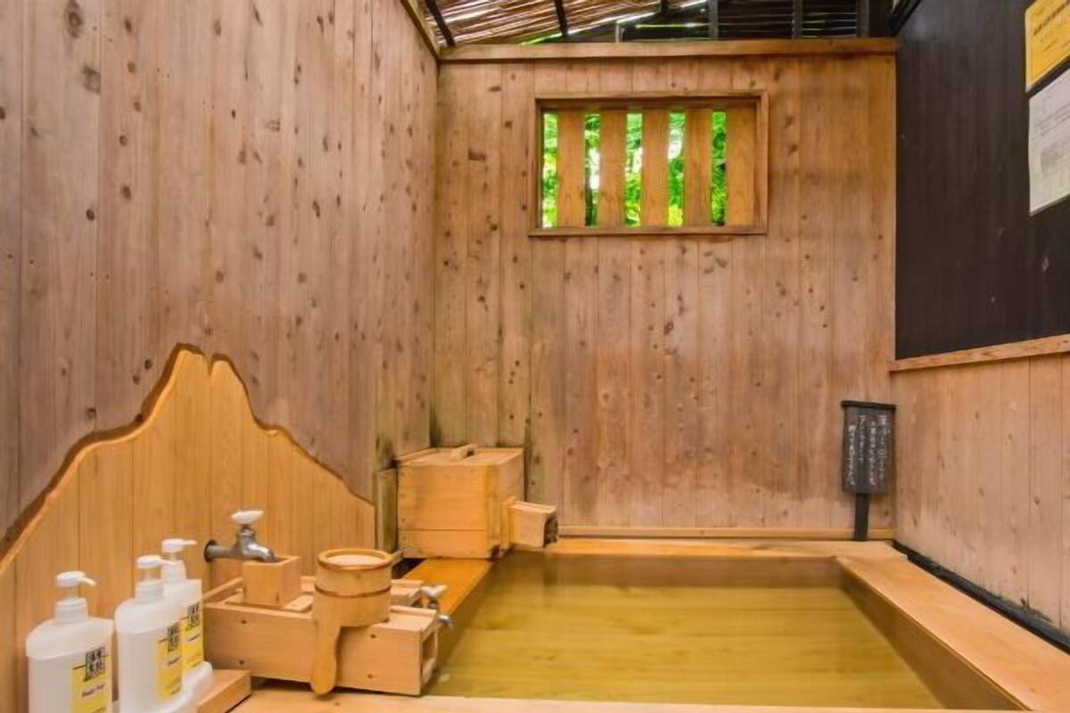 A wooden room with a wooden tub, wooden benches, and a window with vertical slats.