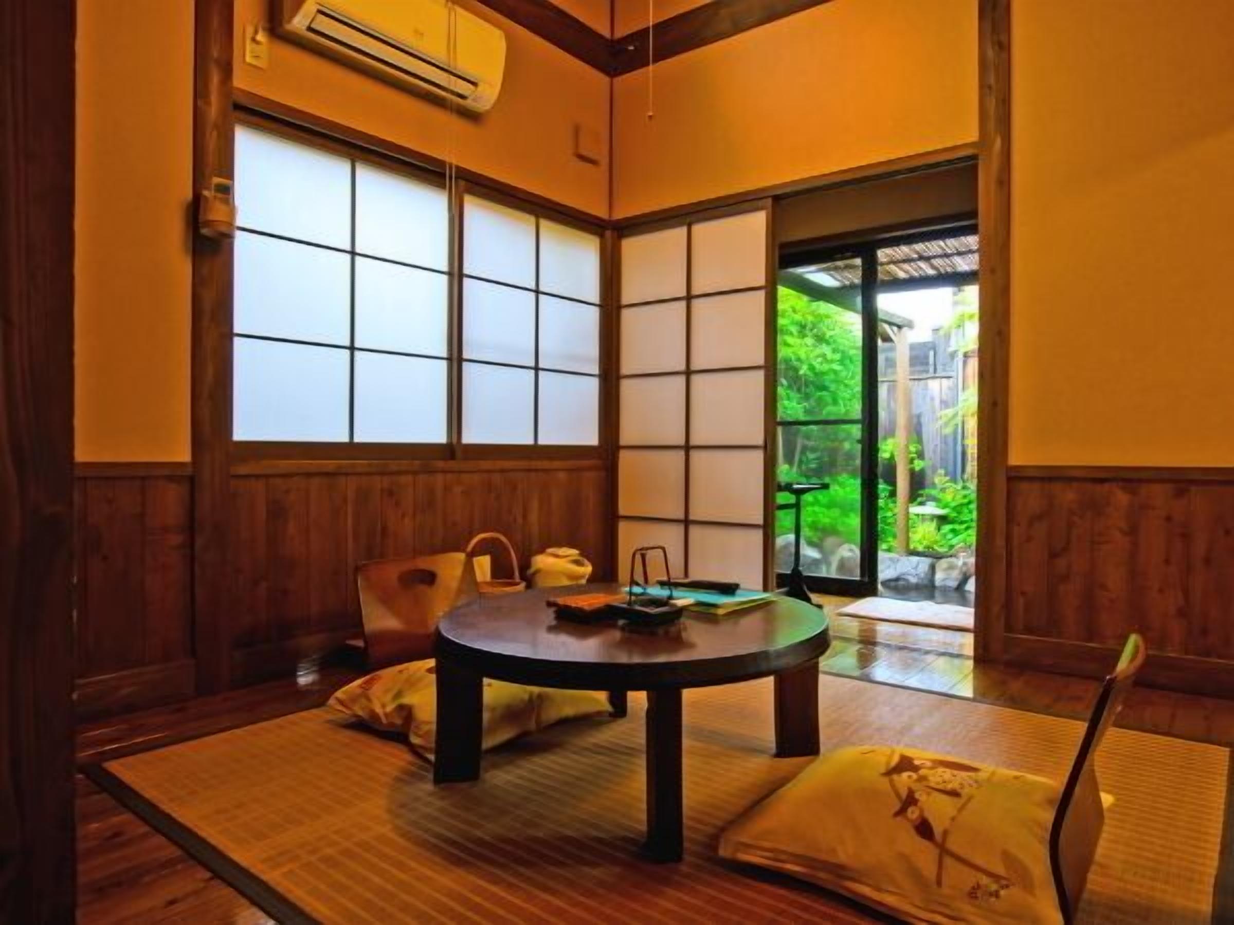 Una habitación tradicional japonesa con suelo de tatami, una mesa baja y puertas correderas.