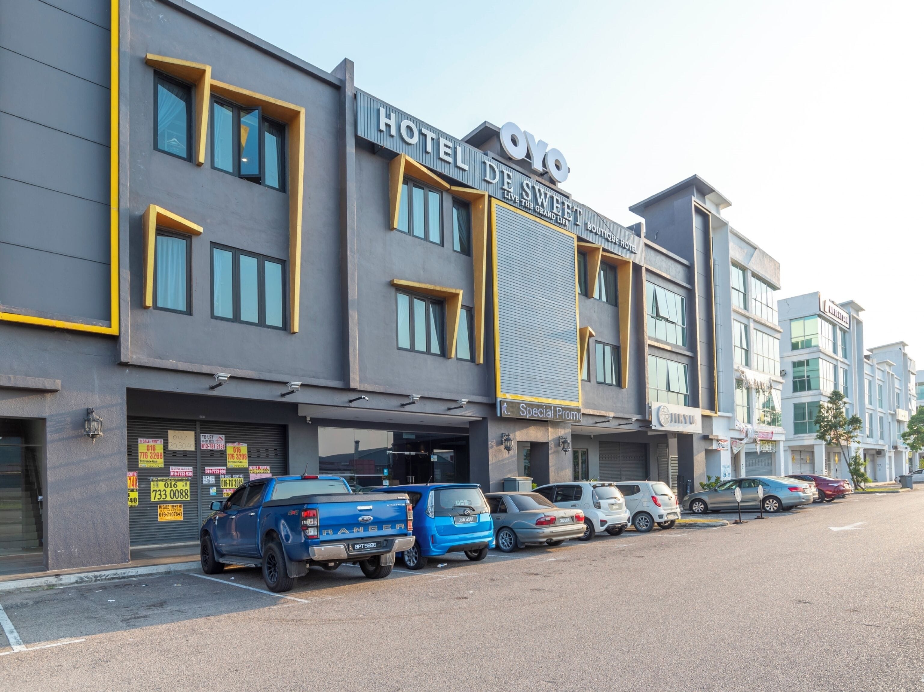 A hotel with a modern facade, multiple parking spaces, and a sign indicating a special promotion.