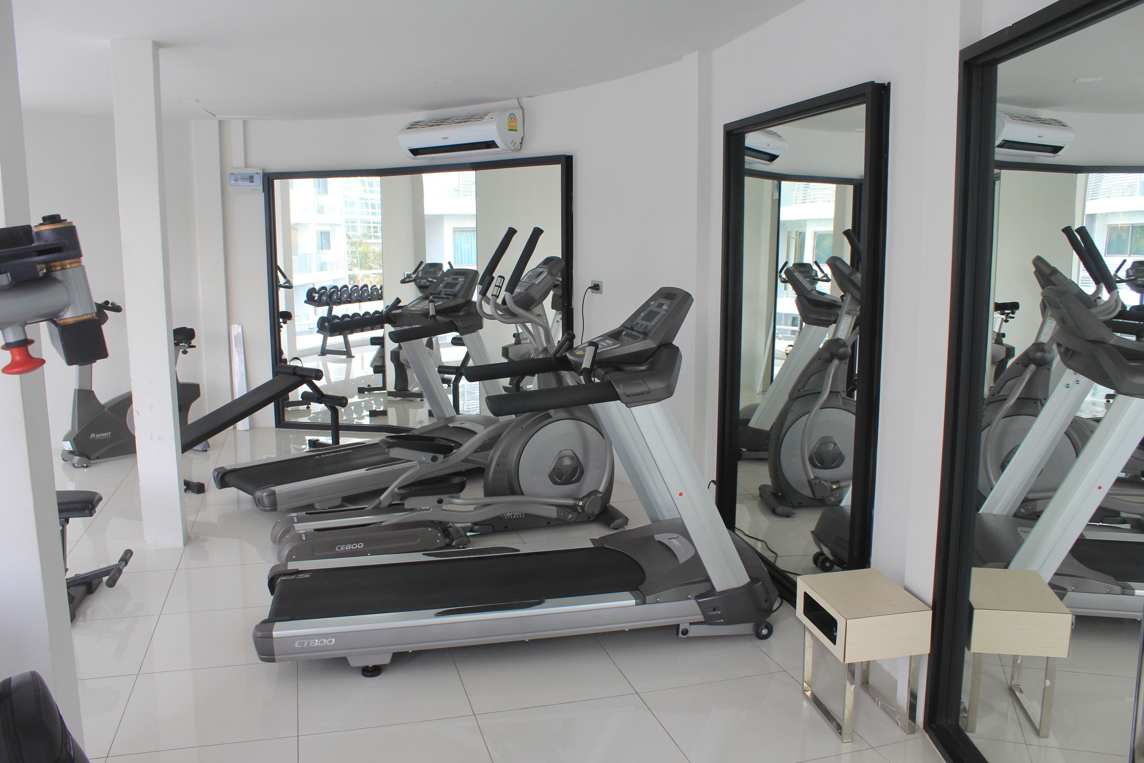 Un gimnasio con cintas de correr, bicicletas estáticas y un soporte para pesas.