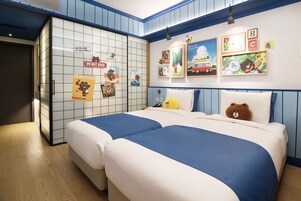 A hotel room with two beds, a wardrobe, and a wall decorated with children's artwork.