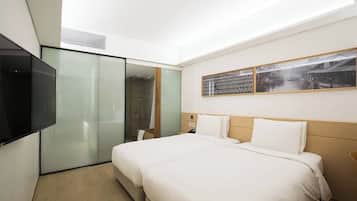 Una habitación de hotel moderna con una cama grande, un televisor montado en la pared y un armario con puerta corredera de vidrio.