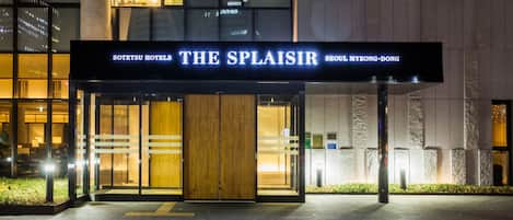 The entrance to Sotetsu Hotels The Splaisir, featuring a prominent sign, a wooden door, and a well-lit facade.
