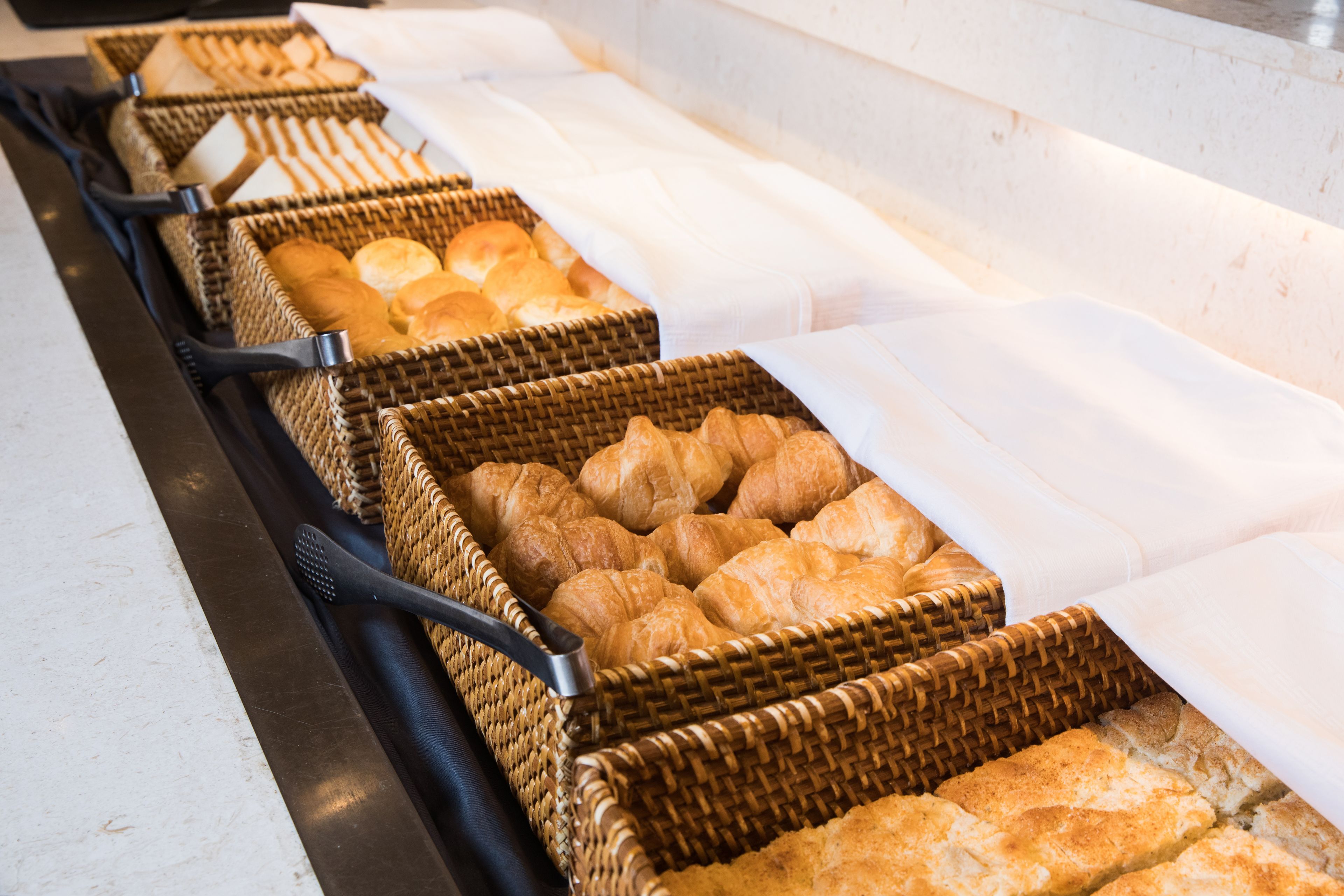 Un bufé con diversas opciones de panadería en cestas de mimbre.