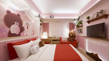 A pink-themed bedroom with a bed, bedside tables, a desk, and a TV.
