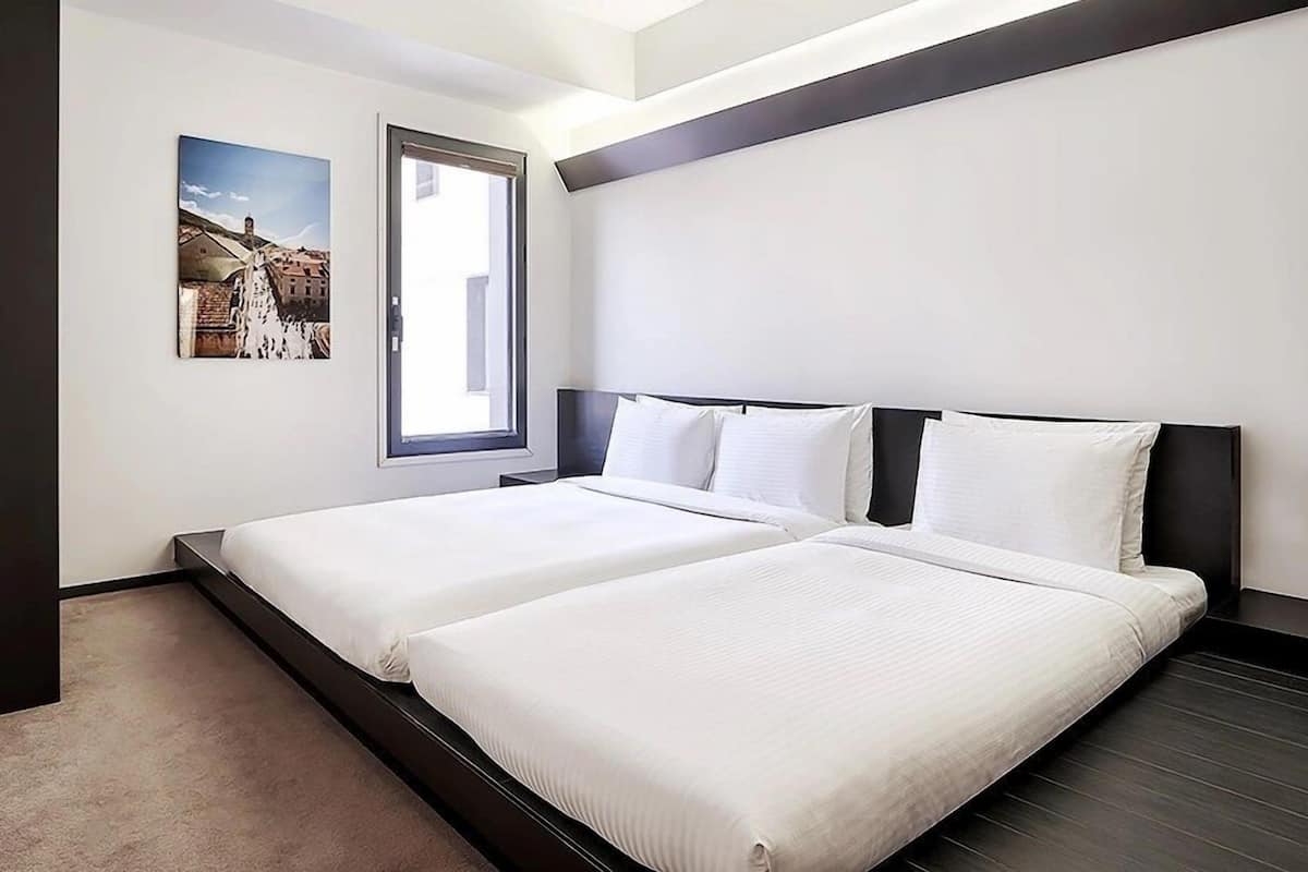 Ein Hotelzimmer mit zwei Betten, einem großen Fenster und einem Wandbild.