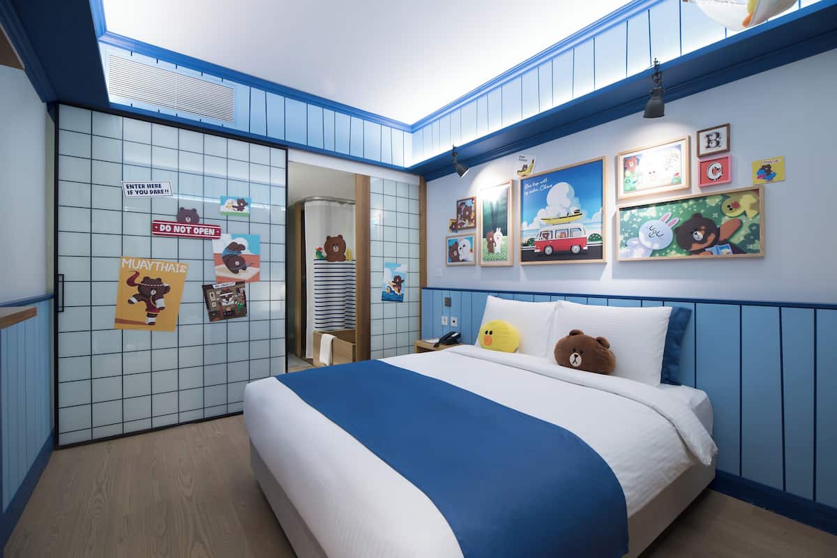 Ein kinderfreundliches Hotelzimmer mit einem großen Bett, einer blauen und weißen Farbgestaltung und verschiedenen Kinderbildern an den Wänden.