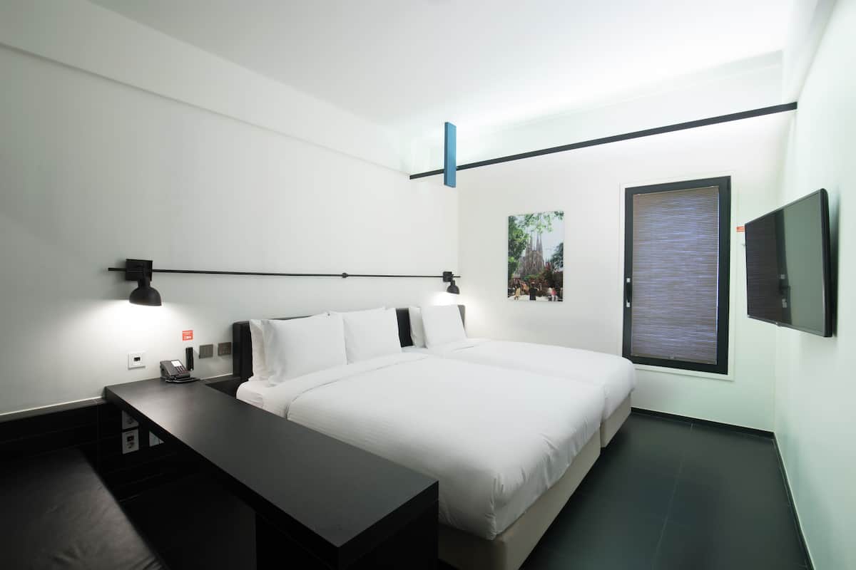 Ein modernes Hotelzimmer mit einem großen Bett, Nachttischen, einem Schreibtisch und einem Fenster mit Jalousien.