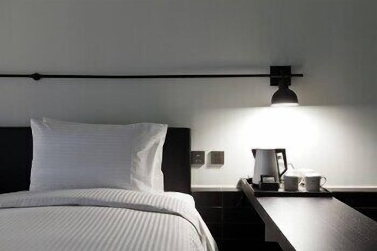 Ein Hotelzimmer mit einem Bett, einem Nachttisch, einer Lampe und einer Kaffeemaschine.