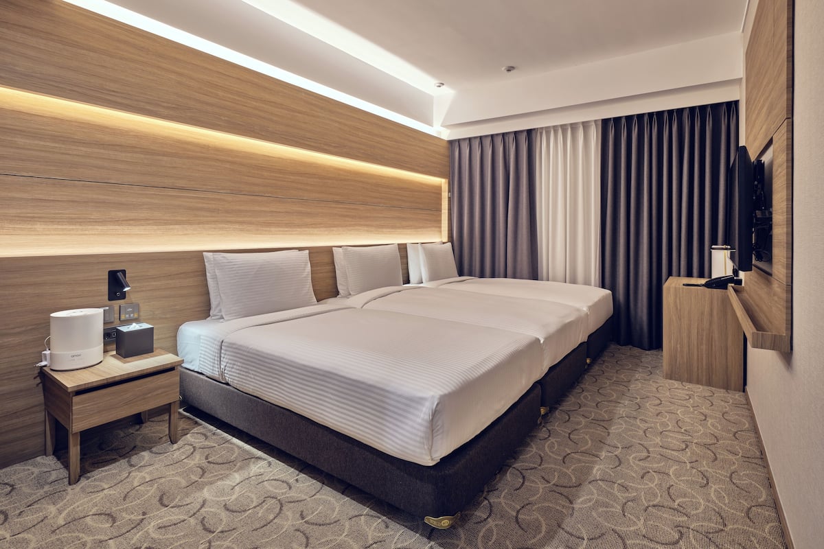 Ein modernes Hotelzimmer mit einem großen Bett, Nachttischen, einem Flachbildfernseher und einer wandmontierten Bedienanlage.