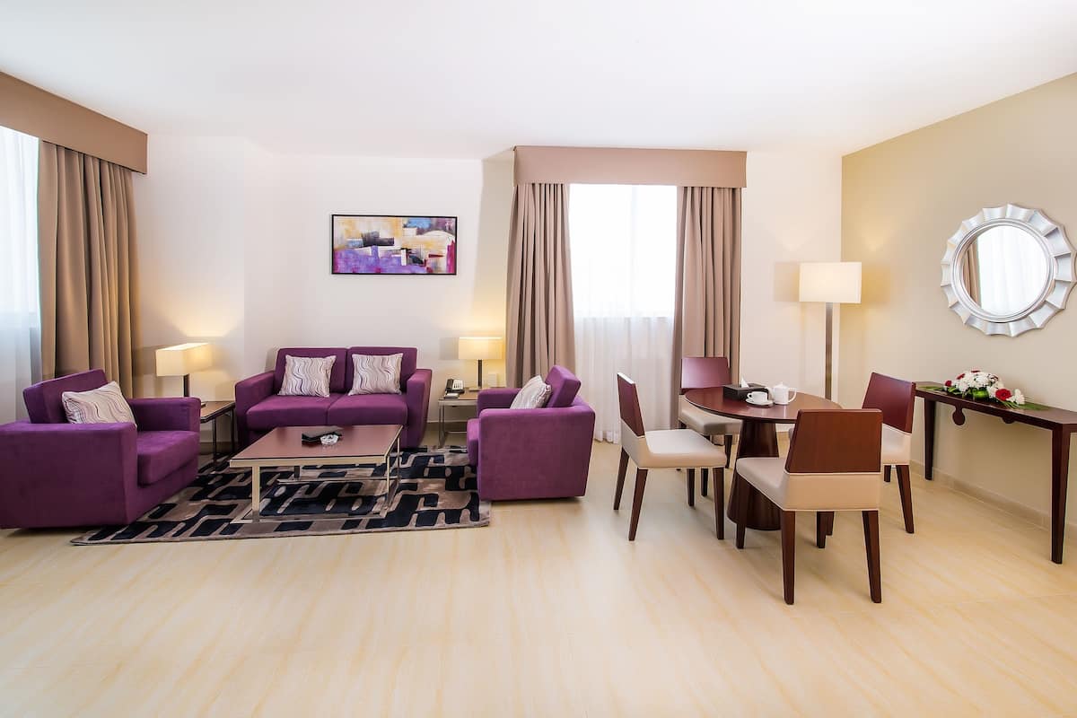 A modern living room with purple sofas, a coffee table, and a dining area with wooden chairs and a table.