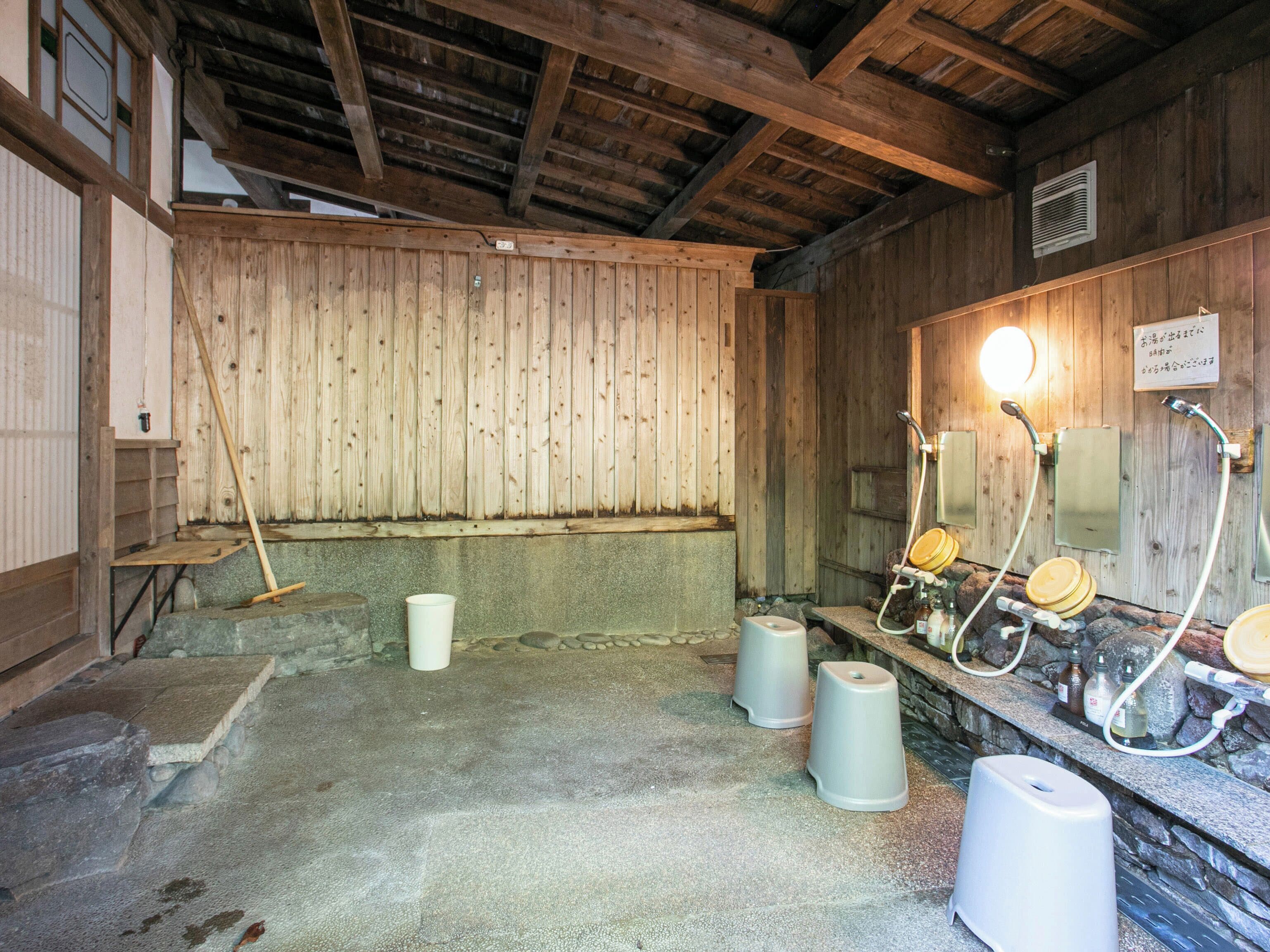 Una sauna de madera tradicional con bancos de piedra, techo de madera y pared de piedra.