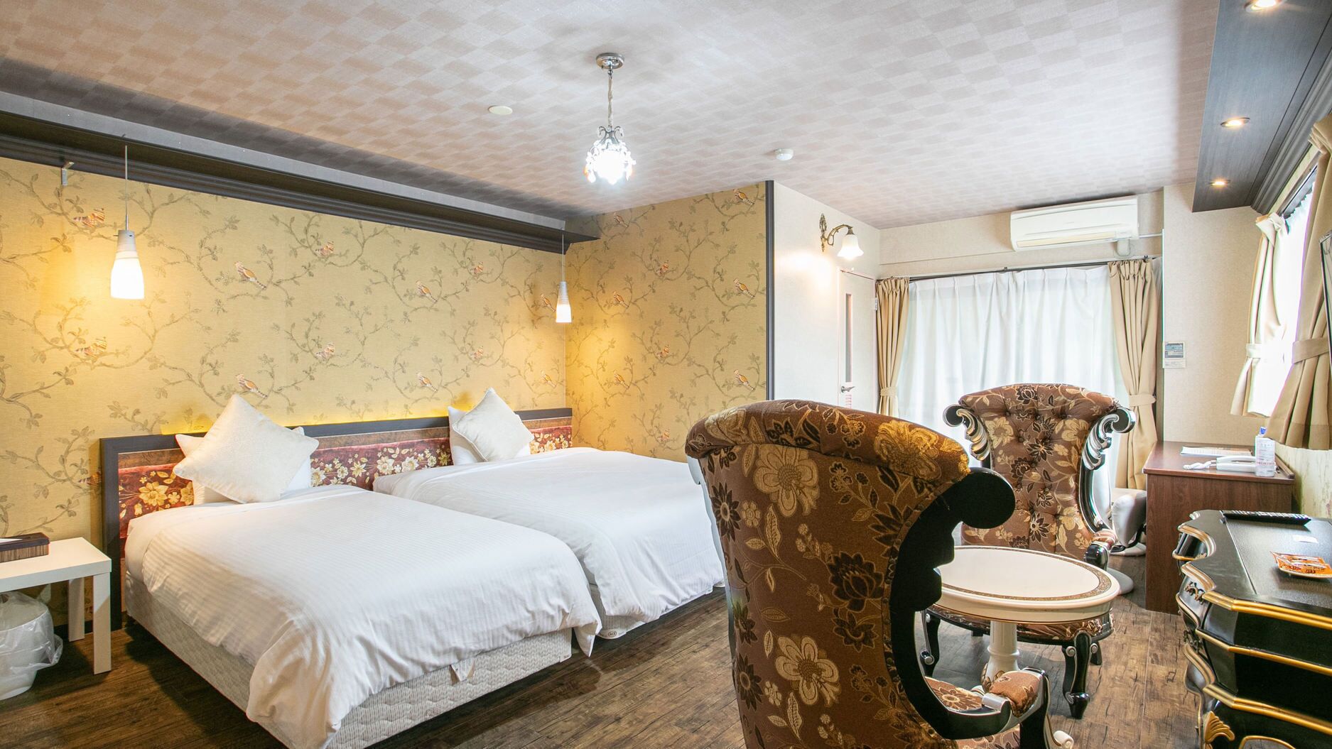 Une chambre d’hôtel avec deux lits, un coin salon avec une table et des chaises, et un grand miroir.