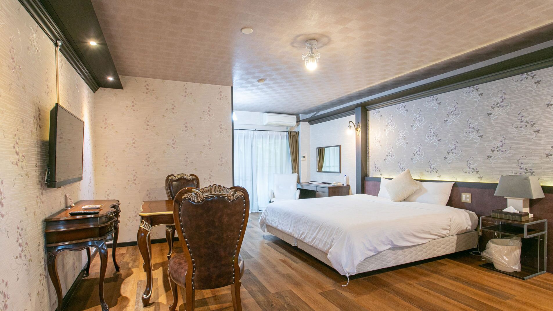 Une chambre d’hôtel équipée d’un lit, d’un bureau, d’une chaise, d’une télévision et d’une fenêtre avec des rideaux.