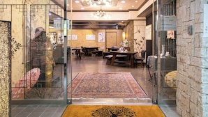 Interior de restaurante con decoración asiática tradicional, que incluye una mesa de madera grande y sillas, un tapete estampado y una lámpara decorativa en el techo.