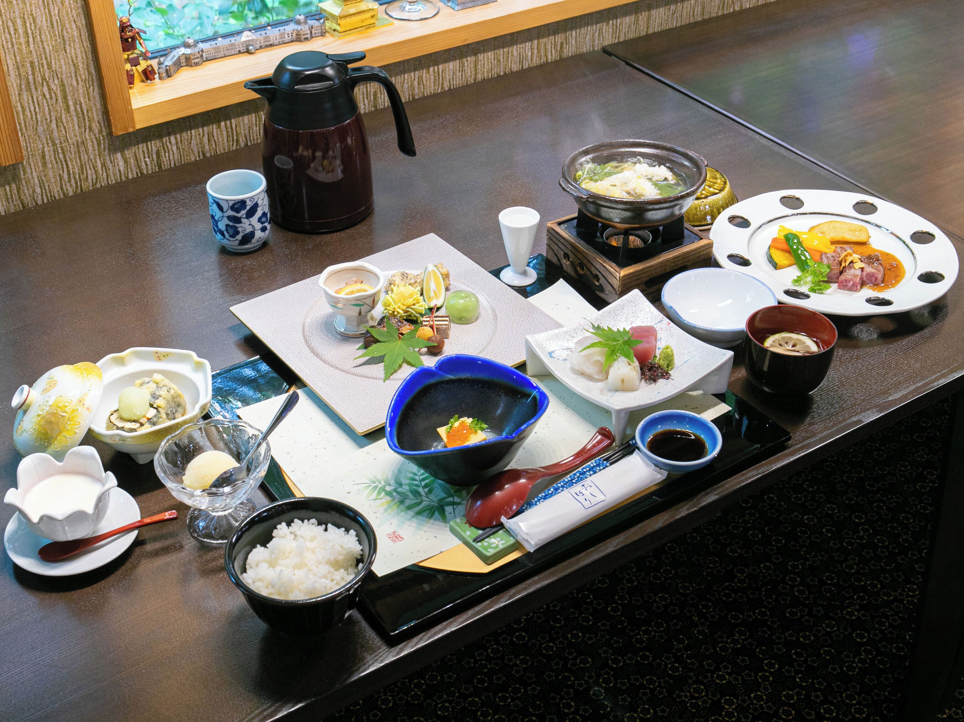 A dining table with various dishes, including sushi, rice, and a hot pot.