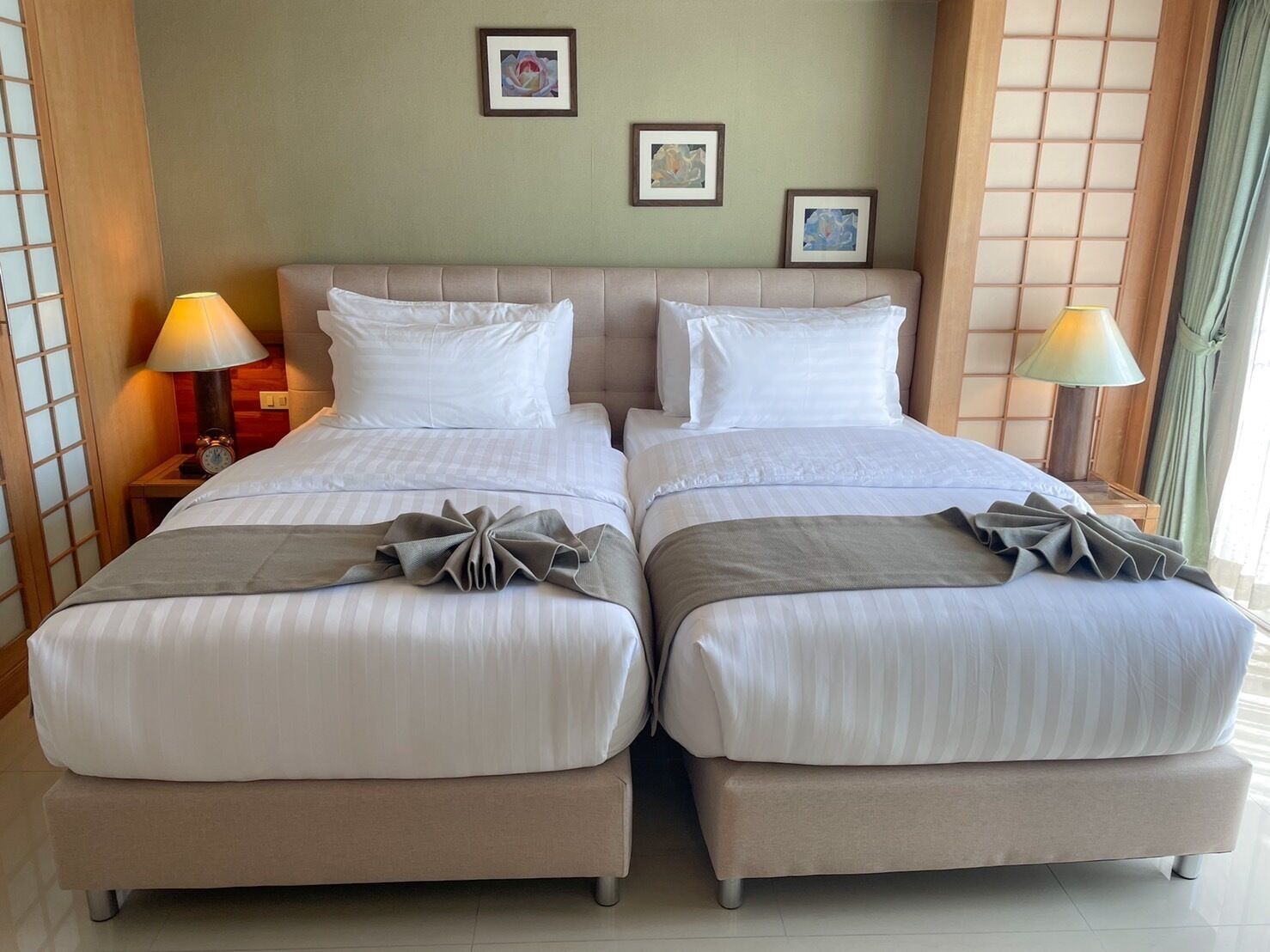 A hotel room with two beds, a wooden headboard, bedside lamps, and artwork on the wall.