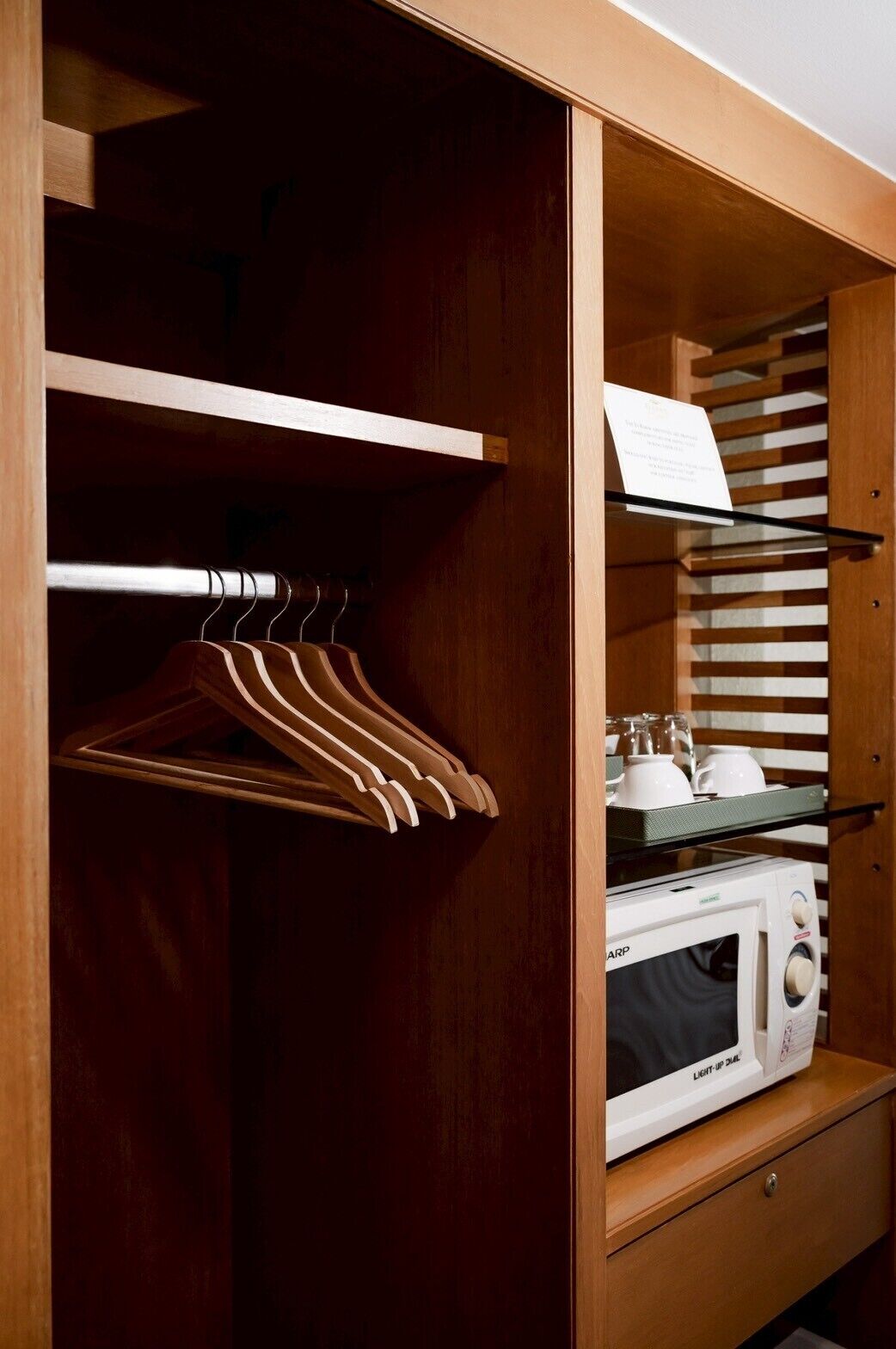 A wooden wardrobe with a hanging rack and shelves containing kitchen appliances.