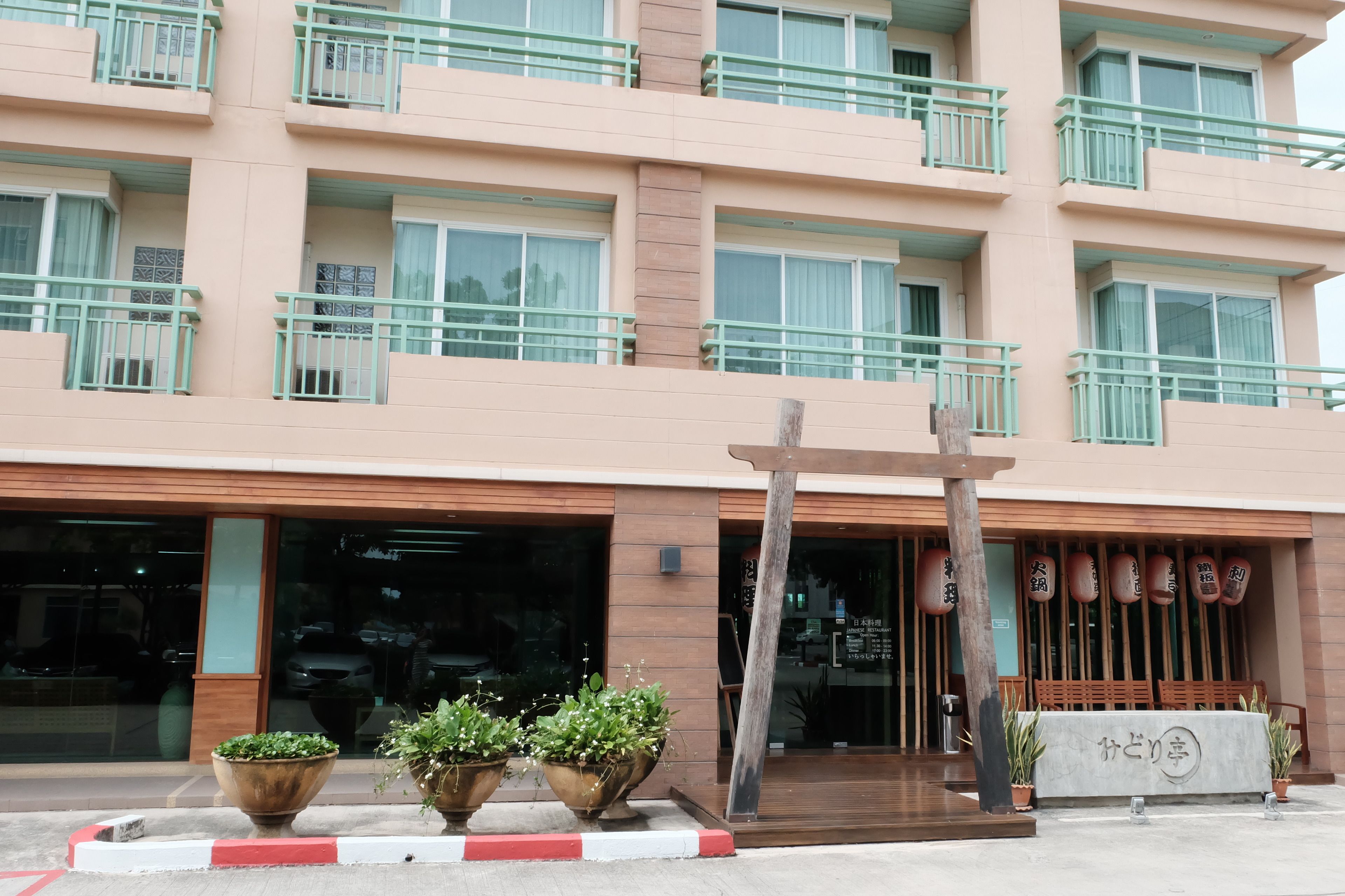 A multi-story building with balconies, large windows, and a wooden entrance.