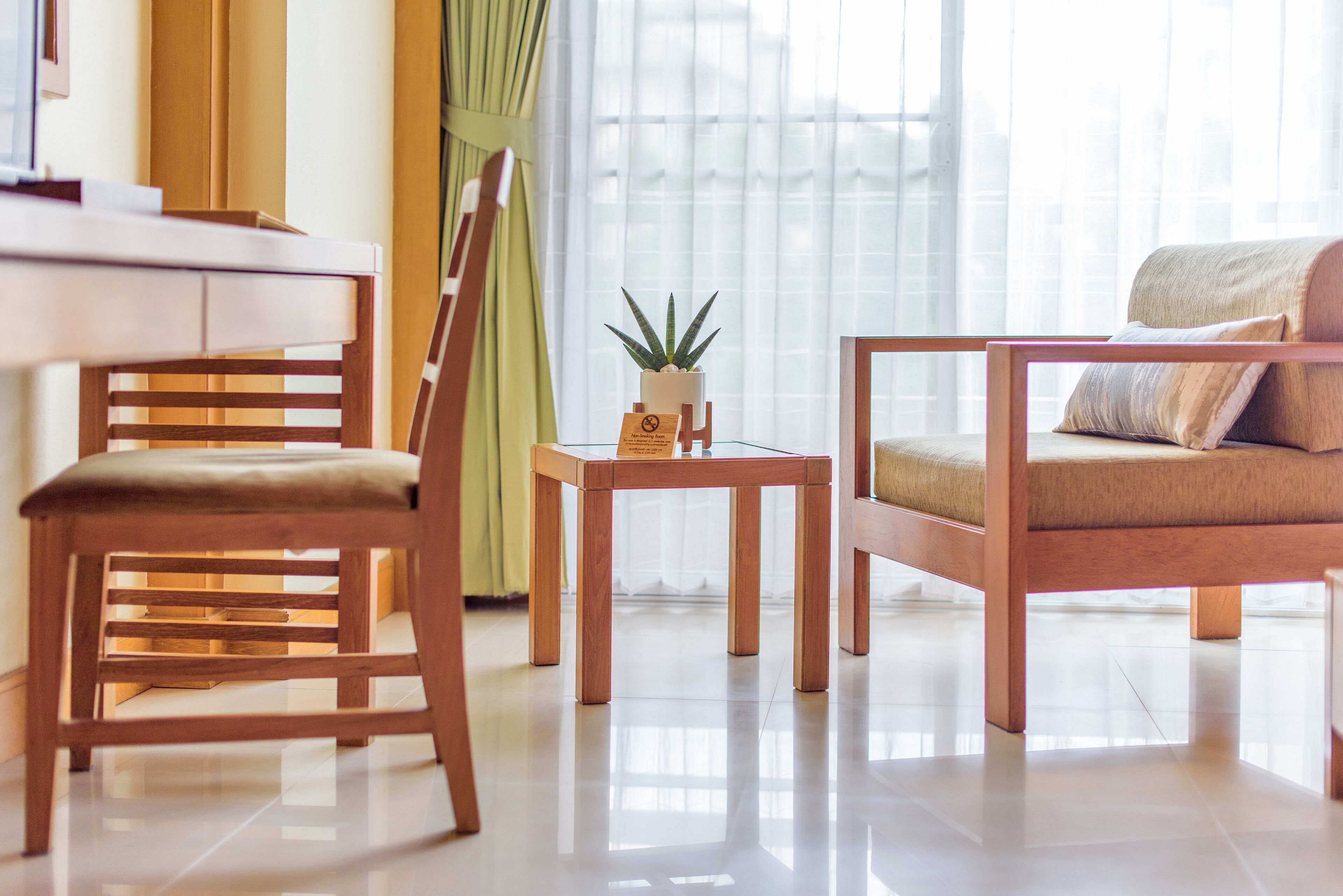 Un salon moderne avec un fauteuil en bois, un canapé et une petite table sur laquelle est posée une plante.