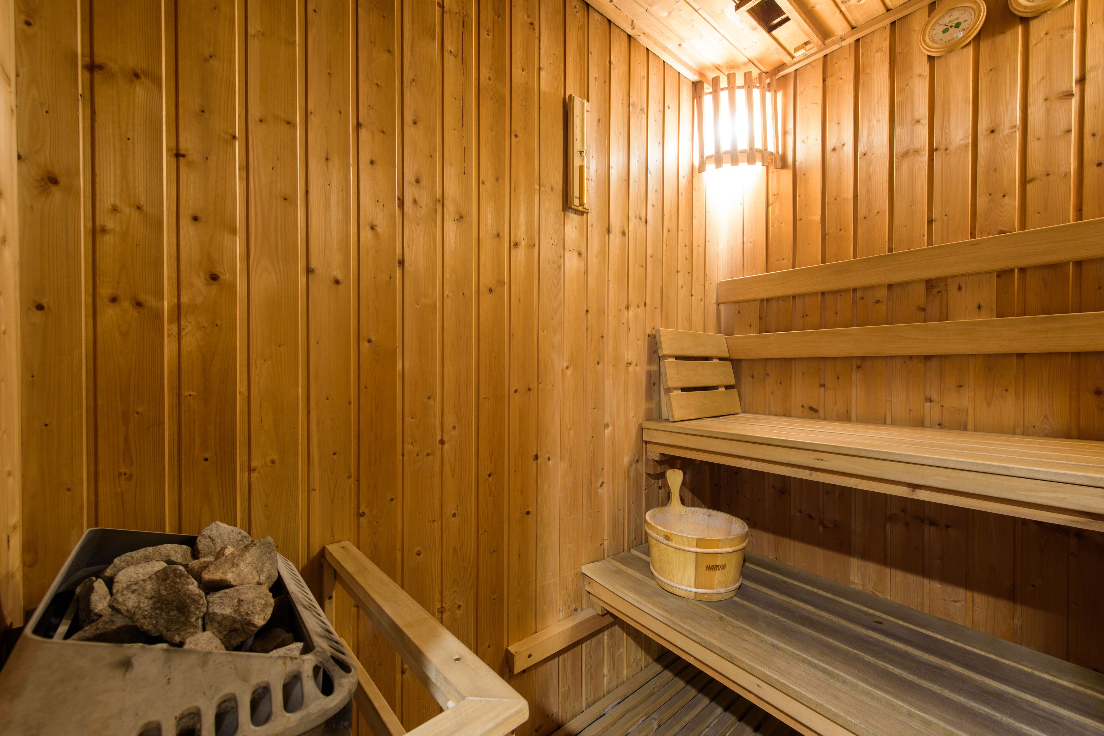A wooden sauna with benches and a bucket.