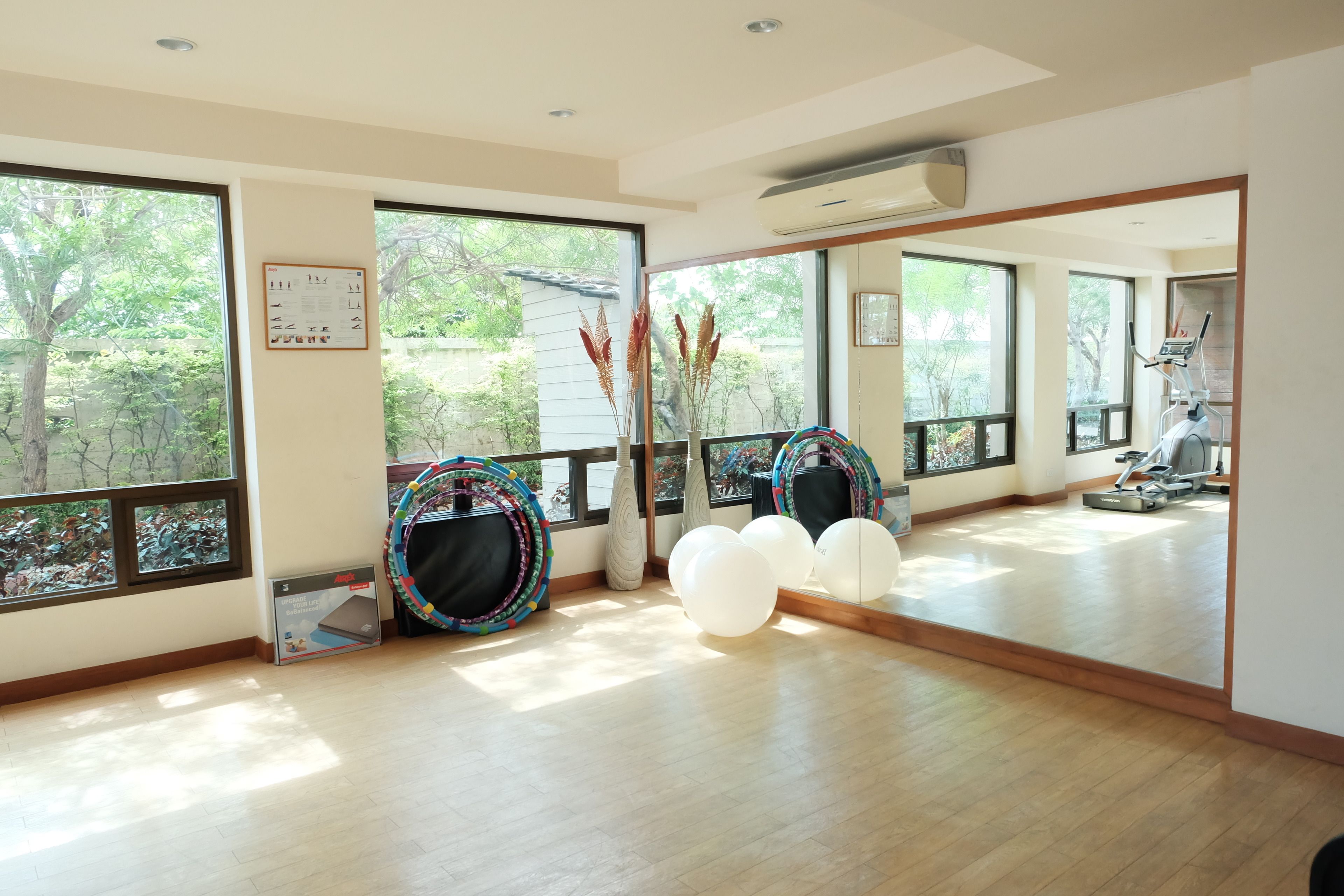 A spacious room with large windows, exercise equipment, and a mirror reflecting the room.