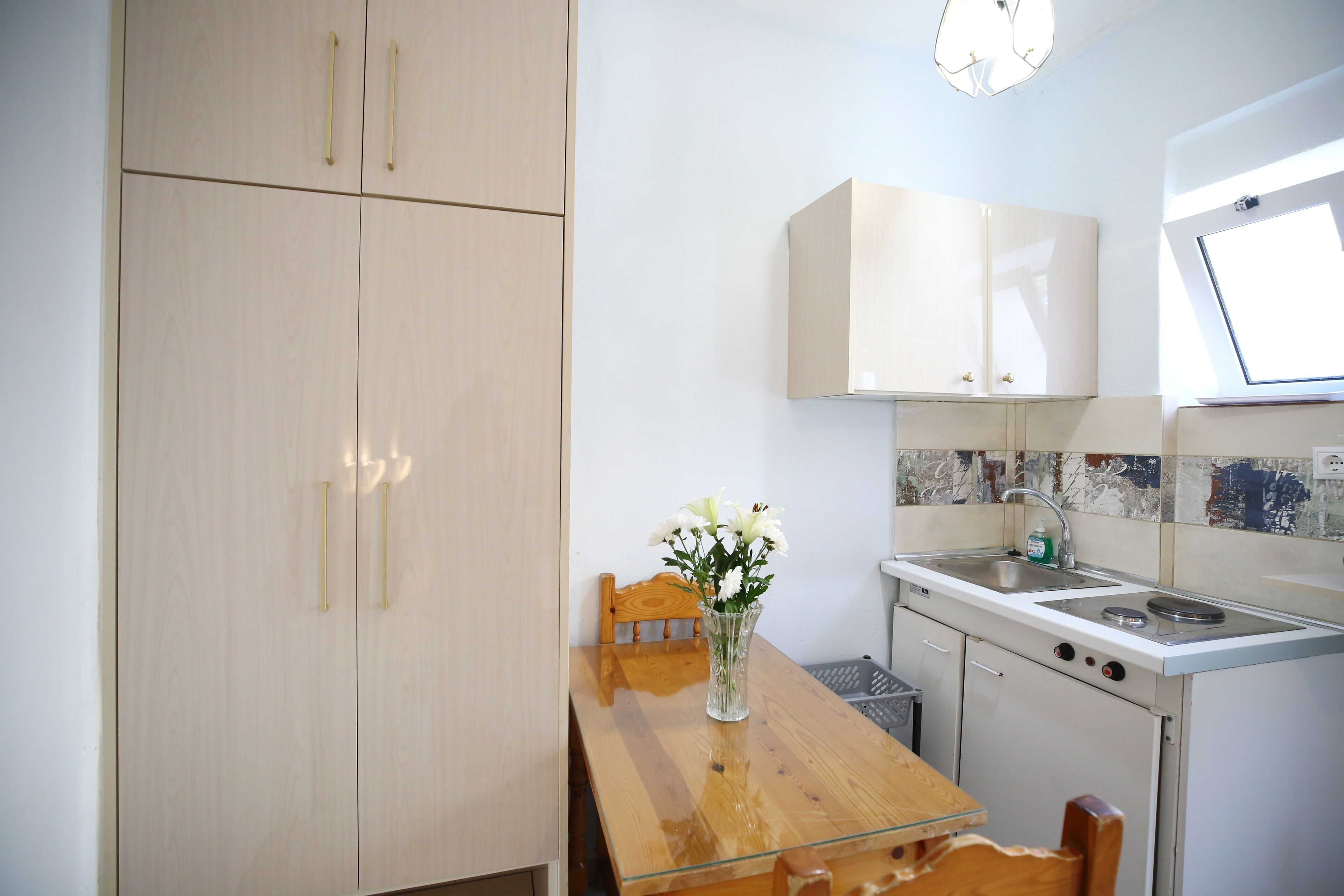 A compact kitchen with wooden cabinets, a wooden dining table, and a small window.