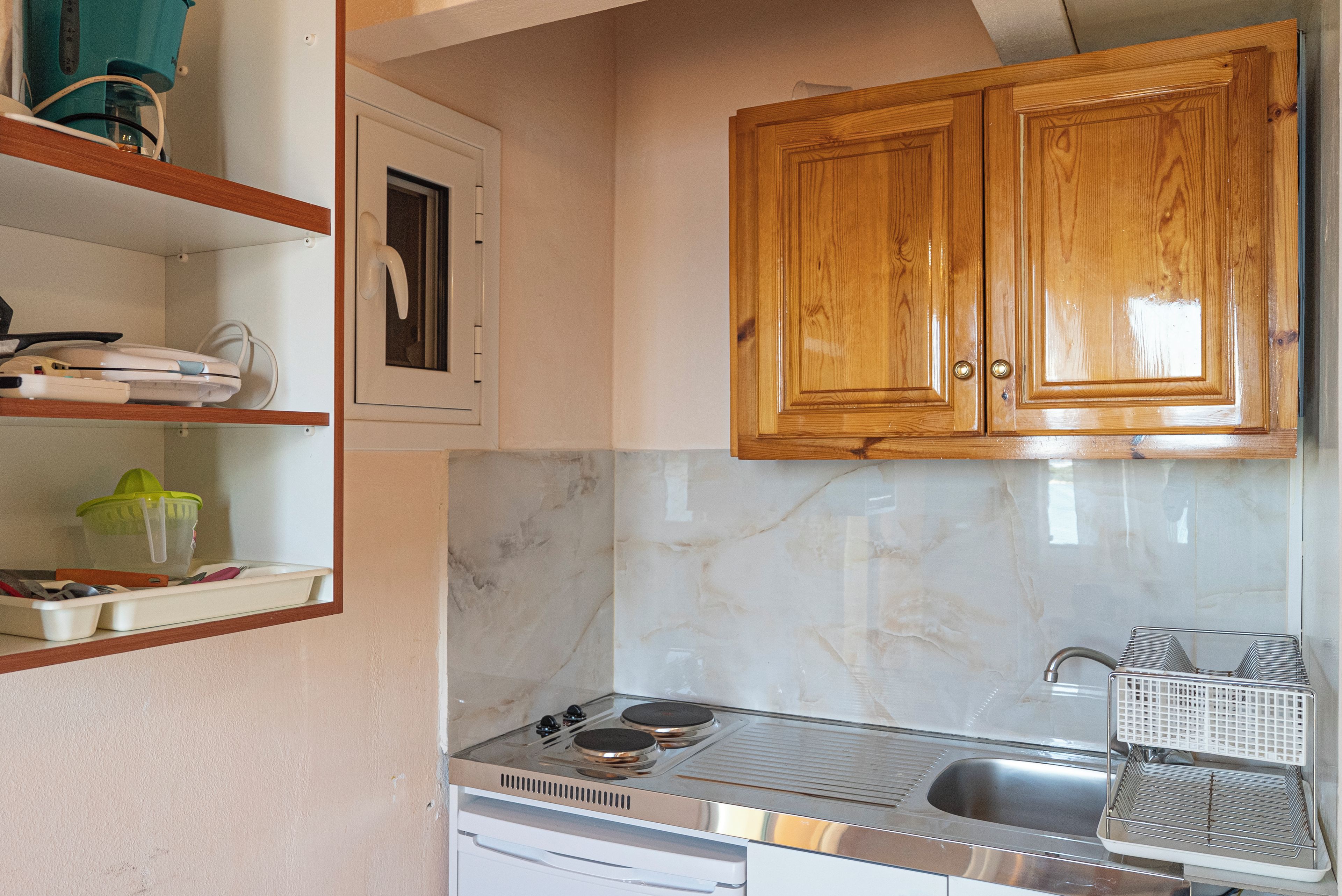 A kitchen with wooden cabinets, a stove, and a sink.