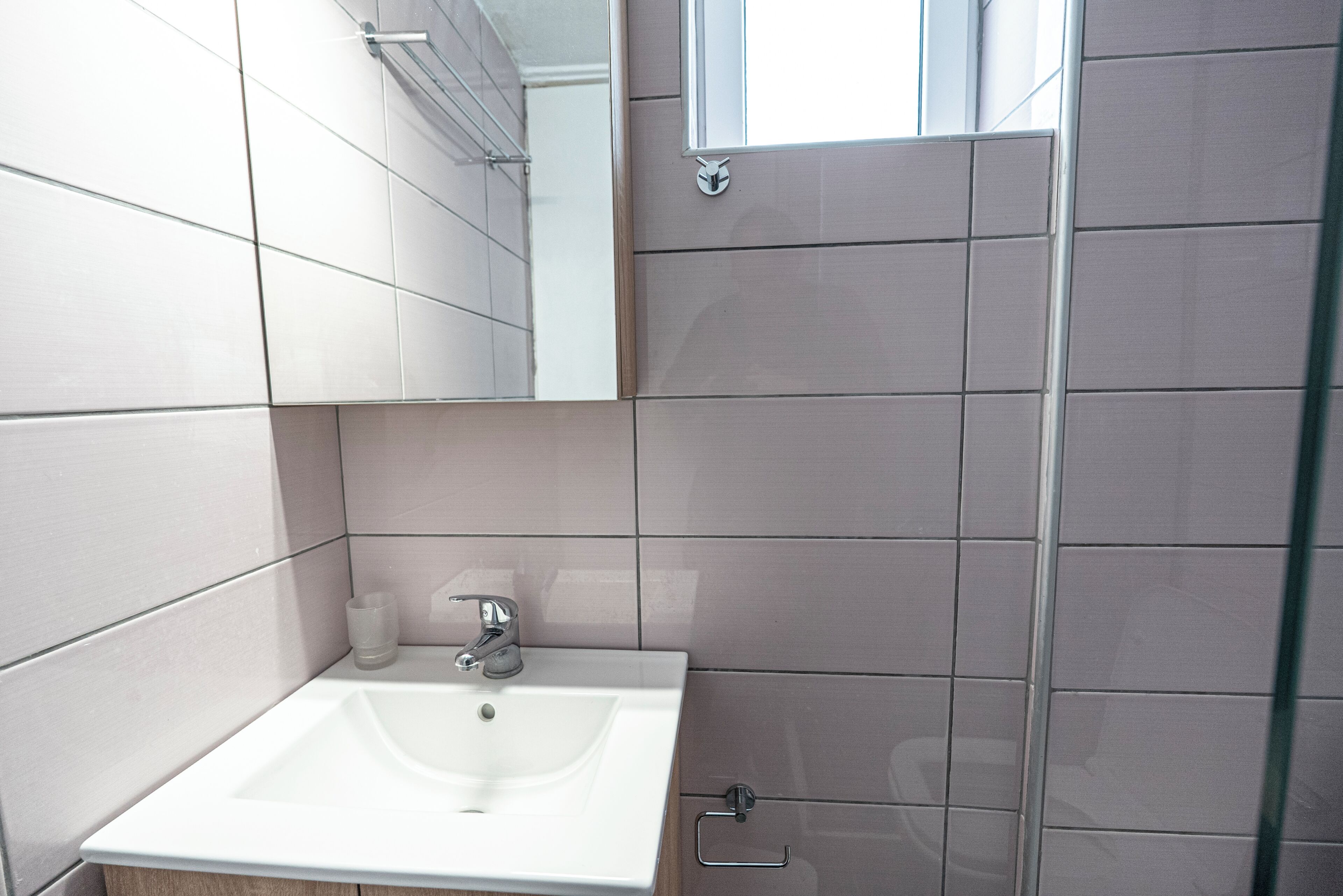 A bathroom with a white sink, a mirror, and tiled walls.