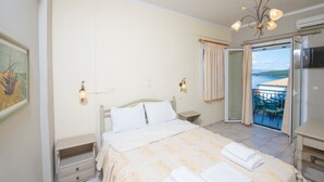Et soveværelse med seng, sengeborde, et natbord, en lysekrone, et maleri og en balkon med udsigt.