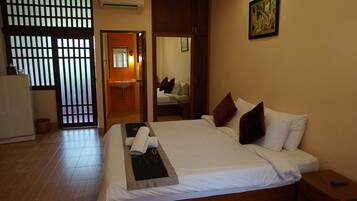 A hotel room with a bed, a bedside table, a mirror, a sink, and a window with blinds.