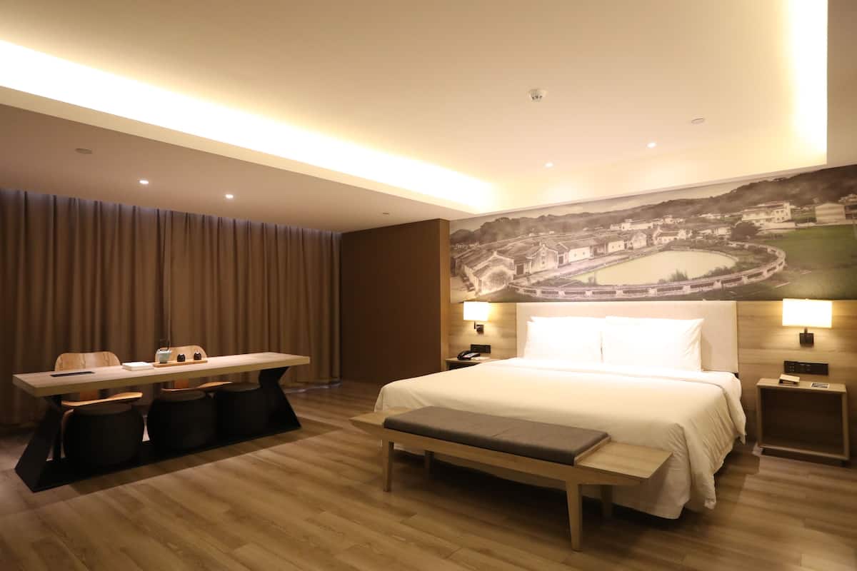 Een moderne hotelkamer met een groot bed, een bureau en een zithoek.