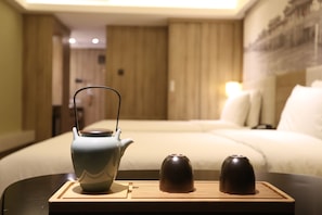 Un juego de té ordenado sobre una bandeja en una habitación de hotel, con una cama y una obra de arte colgada en la pared.
