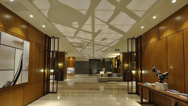 Un hall d’entrée spacieux avec un plafond haut, des lambris en bois, un comptoir de réception et un espace salon.