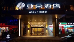 L’extérieur de l’hôtel Atour, avec son entrée moderne et son enseigne lumineuse.