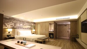 Une chambre d’hôtel avec un lit, une table de chevet, un bureau et une fresque murale.