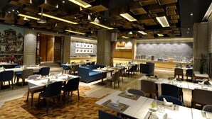 Un restaurant moderne doté de plusieurs espaces de restauration, d’un bar et d’un mur décoratif orné de motifs circulaires.