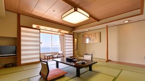 A traditional Japanese room with tatami flooring, a low table with tea set, and a view of the sea through shoji screens. - Hotel Takeshima (Gamagori)