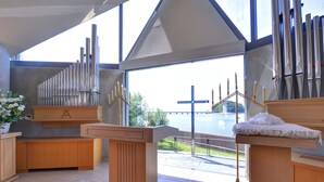 A modern church interior with a large organ, wooden pews, and a view of a river. - Hotel Takeshima (Gamagori)