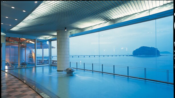 A spacious indoor area with a large window overlooking a body of water and a distant island. - Hotel Takeshima (Gamagori)