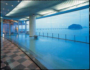 A spacious indoor area with a large window overlooking a body of water and a distant island. - Hotel Takeshima (Gamagori)