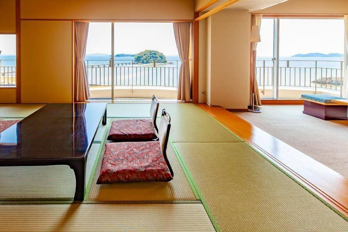 A room with tatami mats, a low table, and a view of the sea.